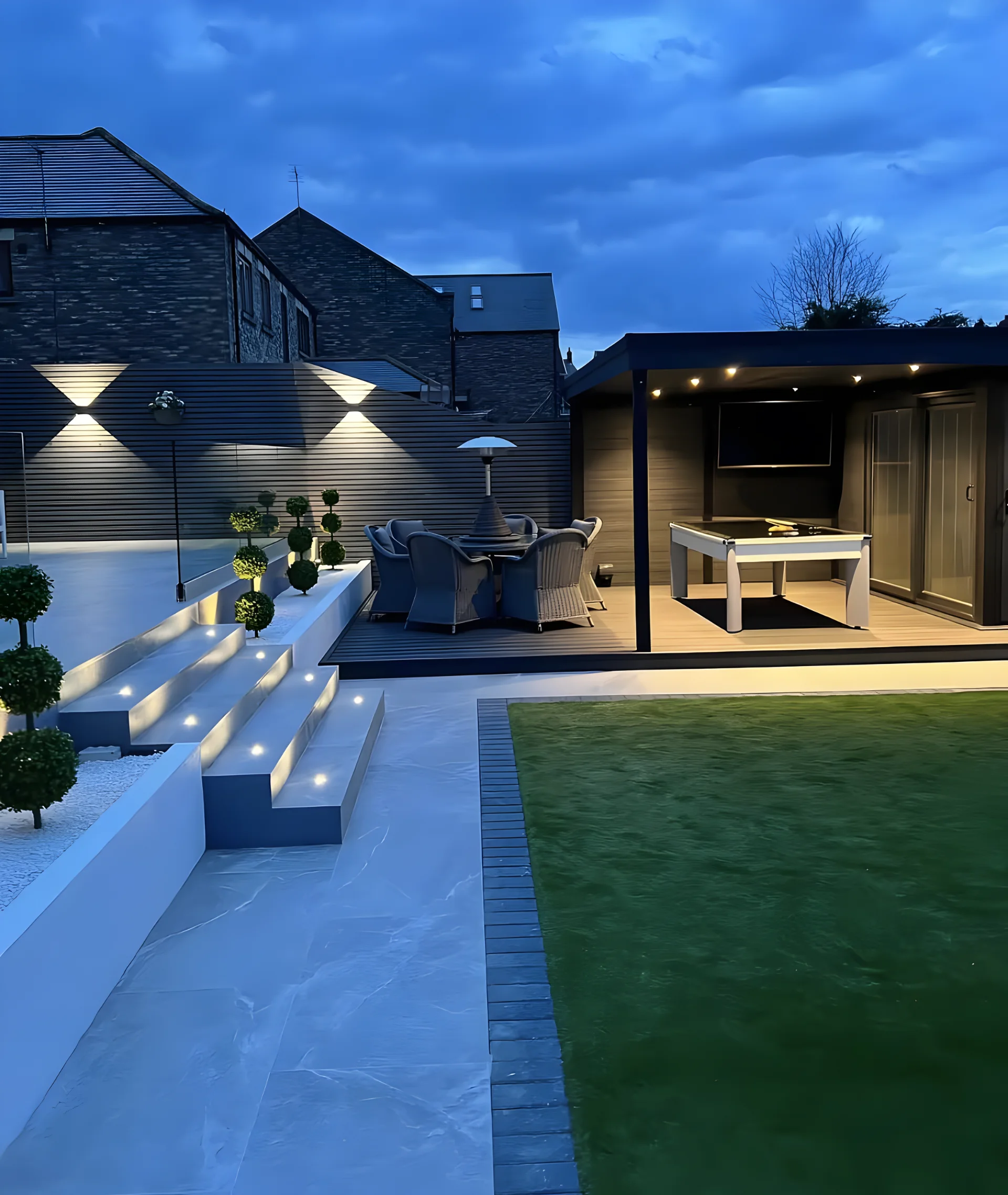 Beleuchtete Terrasse mit Sitzmöbeln und Tisch als Beispiel für HashTEC-Gartenpflege bei Privatkunden in Osnabrück.